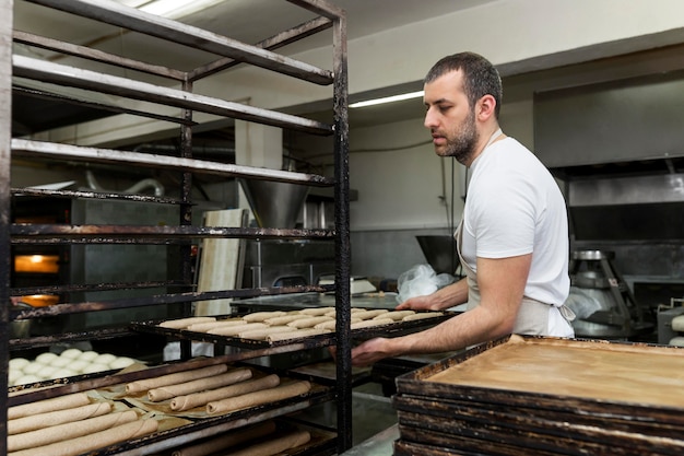 Padeiro moldando pães na produção da padaria
