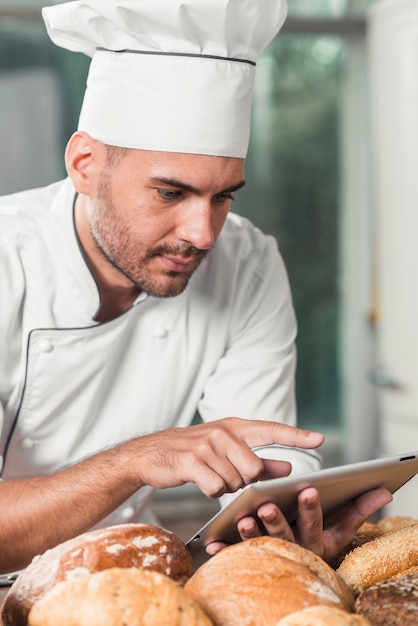 Padeiro consultando o estoque no tablet ao lado dos pães